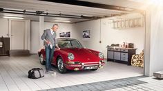 a man standing next to a red car in a garage with luggage on the floor