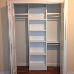 an empty walk in closet with white shelving and wood flooring on the side