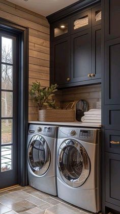 a washer and dryer in a room with wooden walls, black cabinets and tile flooring