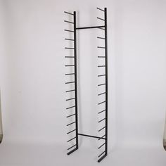 two tall black metal racks on the wall next to each other and one is empty