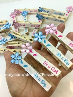 small wooden clips with flowers on them are being held in someone's hand,