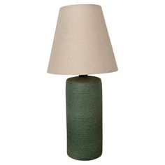 a green table lamp with a white shade on the base and a beige linen lampshade