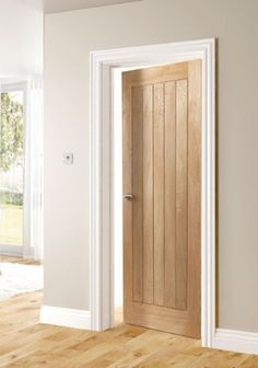 an open door in a white room with wooden floors and chairs on the side table