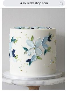 a white cake with blue and green flowers on it