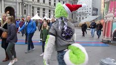 a man in a green and white costume is walking down the street with other people