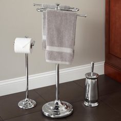 a towel rack with two towels hanging from it's sides next to a toilet paper dispenser