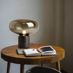 a table with a lamp on top of it next to a book and a chair