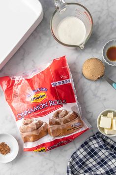 ingredients to make cinnamon rolls laid out on a marble counter top, including butter and sugar