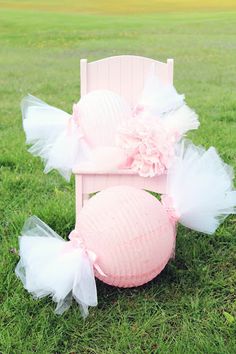 a pink chair sitting in the grass with tulle skirt on it's back