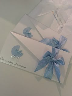 two cards with blue bows on them are laying next to each other in envelopes