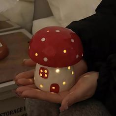 a woman holding a lit up mushroom shaped object in her hands with lights on it