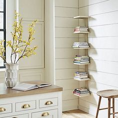 a room with white walls and wooden flooring has a book shelf on the wall