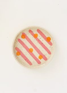 a white plate with pink and orange designs on it's rim, against a white background