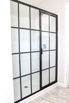 a bathroom with a glass shower door and tile flooring on the side of the wall