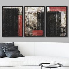 two black and red paintings hanging on the wall above a white couch in a living room