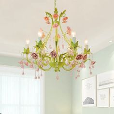 a chandelier hanging from the ceiling in a room with green walls and pink flowers