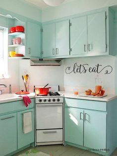 a kitchen with light blue cabinets and white appliances, including an electric stove top oven