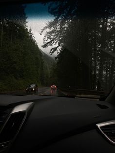 the dashboard of a car driving down a road with trees in the backgroud