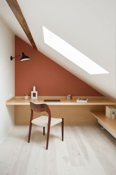 a chair and desk in the corner of a room with an orange wall behind it