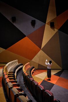 a woman standing in front of an auditorium filled with empty seats and looking up at the ceiling