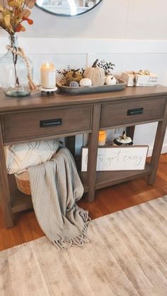 a wooden table with two drawers and a mirror on the wall next to it in a living room