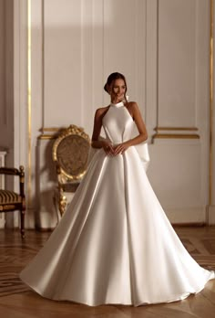 a woman in a white wedding dress standing on a wooden floor