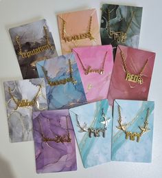 there are many different colored bags with gold letters on them, and one has a name necklace