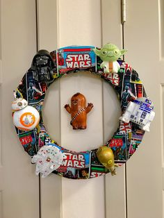 a star wars wreath hanging on the front door with toys around it and an ornament in the middle