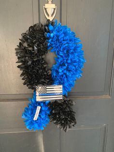 a wreath with an american flag on it hanging from the front door, next to a pair of scissors