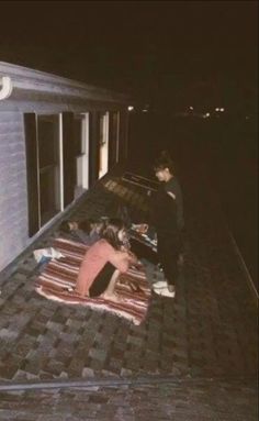 two people laying on the roof of a house at night