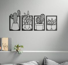 three black and white pictures hanging on the wall above a bed with a pillow, potted plants and a cardboard box