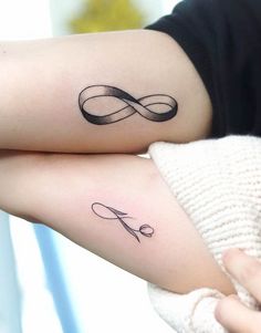 two people with matching tattoos on their arms, one is holding the other's arm