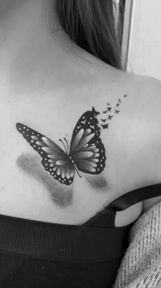 a black and white photo of a butterfly on the back of a woman's shoulder