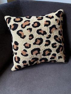 a leopard print pillow sitting on top of a gray couch