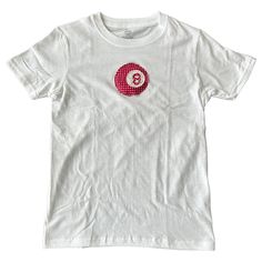 a white t - shirt with a red and white button on it