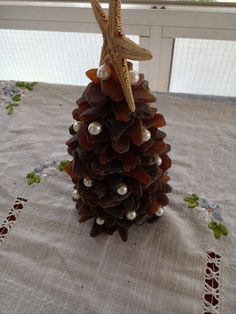 a pine cone with pearls and starfish on it sitting on top of a table