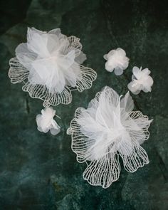 three white flowers with tulle attached to them