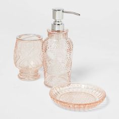 a glass bathroom set with soap dispenser and toothbrush holder