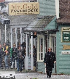 people are walking in the snow outside of a pawnbroker's shop on a snowy day