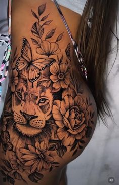 a woman's stomach with flowers and a lion tattoo on the side of her body