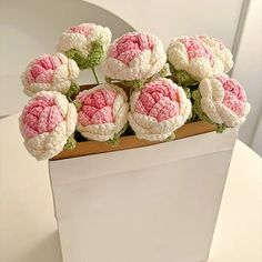 a white vase filled with pink and white crocheted flowers on top of a table