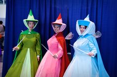 three women dressed in costume standing next to each other on a stage with blue curtains behind them