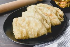 some food is on a black plate next to a rolling pin and a glass container