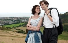 a man and woman standing next to each other on top of a grass covered field