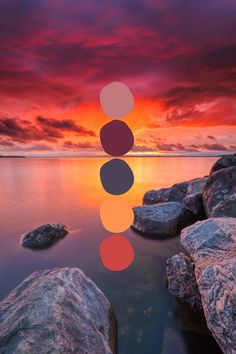 the sun is setting over some rocks in the water and there are three circles on top of them