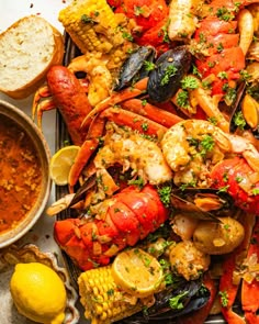 a platter with lobsters and corn on the cob next to some bread