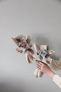 two bridesmaids holding bouquets of flowers in their hands on a gray background