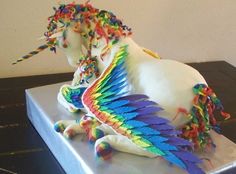 a white horse with multicolored feathers on it's head and tail sitting on top of a table