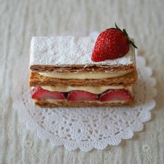 a piece of cake sitting on top of a doily with a strawberry on top