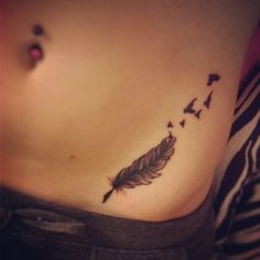 a woman's stomach with a feather tattoo on it